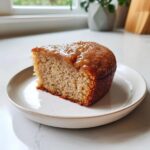 A slice of homemade Apple Cake for Dogs on a white plate, showing the moist texture and golden-brown top.