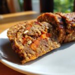 Slices of Beef Dog Food Roll Recipe with Carrots and Oats on a plate, showing visible carrots and oats.