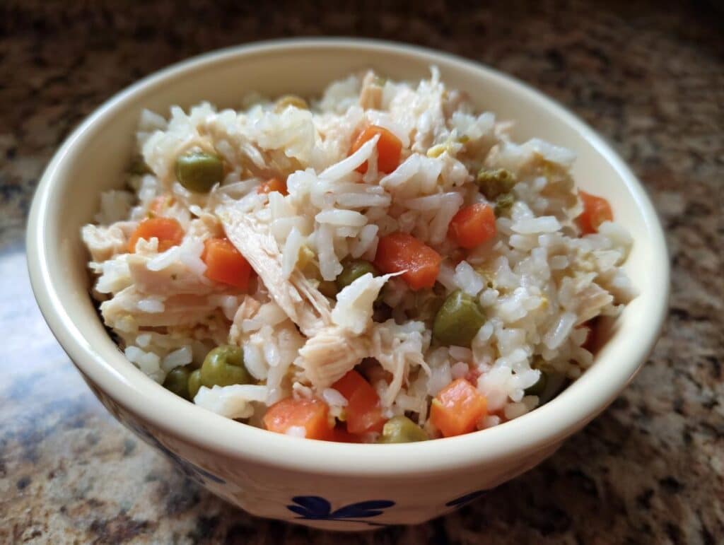 Bowl of homemade Chicken and Rice Dog Food with chicken, rice, carrots, and peas.
