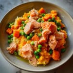 Bowl of Fish and Veggie Delight DOG RECIPE featuring salmon, peas, and carrots.