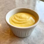 A bowl of creamy, yellow Homemade Banana Smoothie for Dogs, ready to be served as a tasty treat.