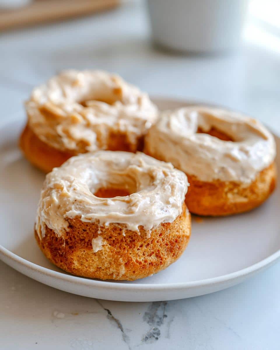 Three peanut butter dog donuts on a white plate, ready to be enjoyed. These are from our Dog Donuts Recipe.