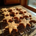 Freshly baked star-shaped Peanut Butter and Honey Dog Treats cooling on a wire rack.