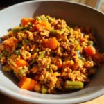 A bowl of homemade Slow Cooker Dog Food Recipes with ground meat, rice, carrots, and green beans.