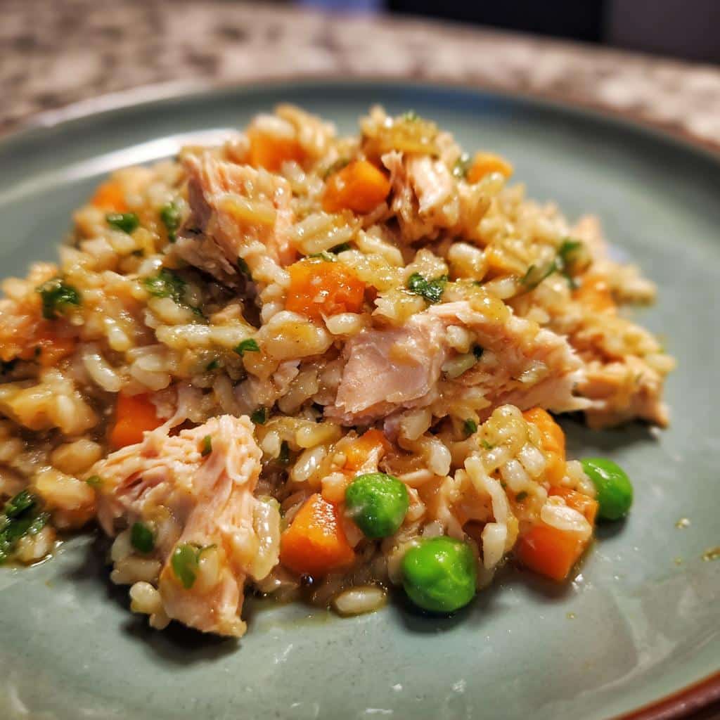 A serving of Baked Salmon & Oats Dog Meal on a green plate, featuring salmon, oats, carrots, and peas.