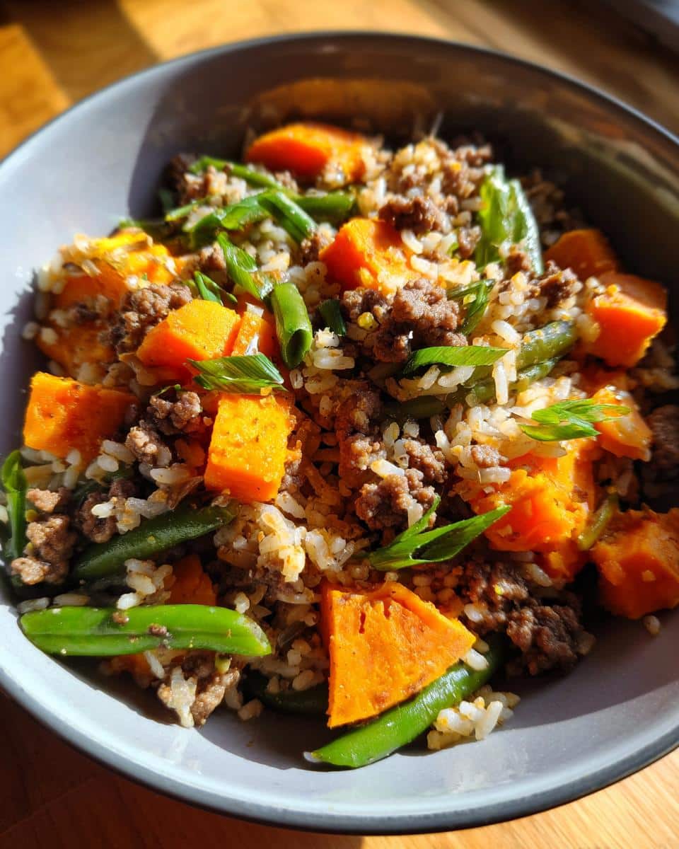 A bowl of Fan-Favorite Beef & Sweet Potato Dog Dinner with beef, sweet potato, rice and green beans.