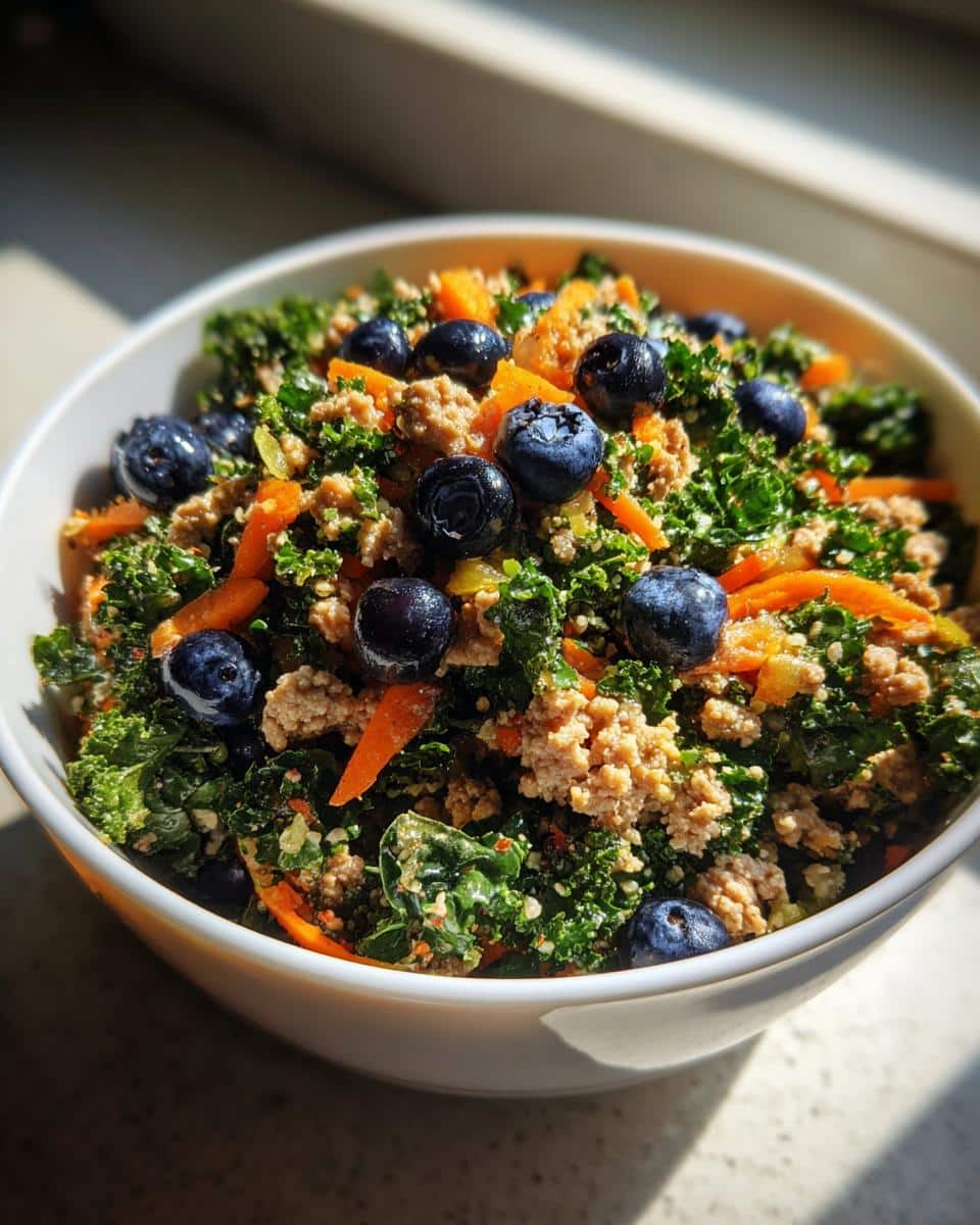 A bowl of Raw Turkey & Kale Dog Recipe with blueberries and carrots, ready to serve to your happy pup.