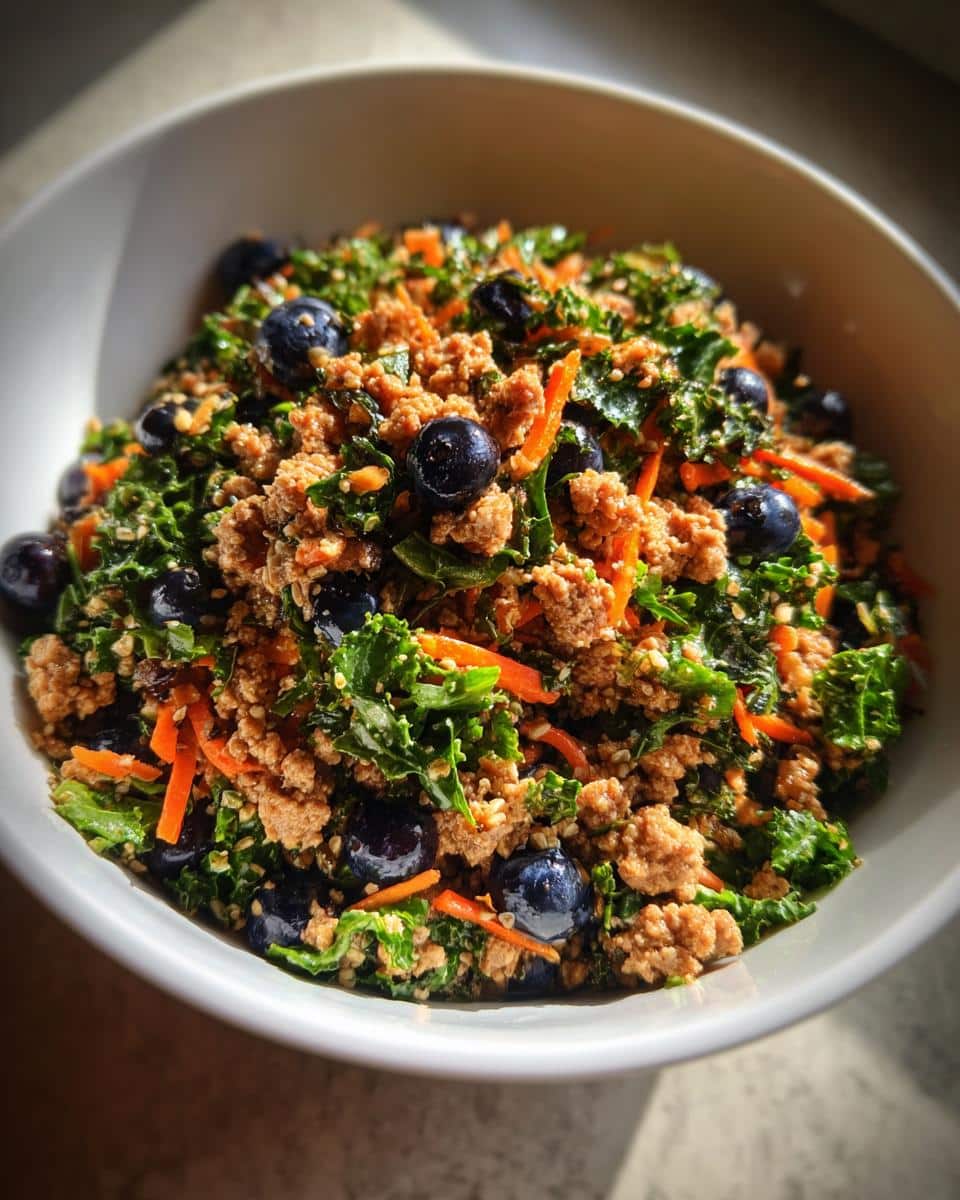 A bowl of Raw Turkey & Kale Dog Recipe, featuring ground turkey, kale, shredded carrots, and blueberries.