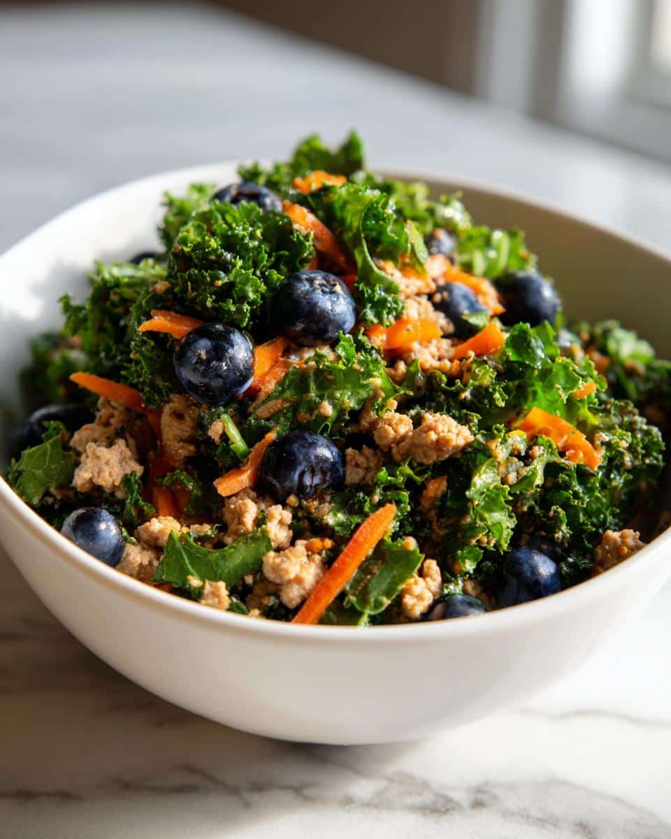 A bowl of Raw Turkey & Kale Dog Recipe, featuring kale, turkey, blueberries, and carrots.