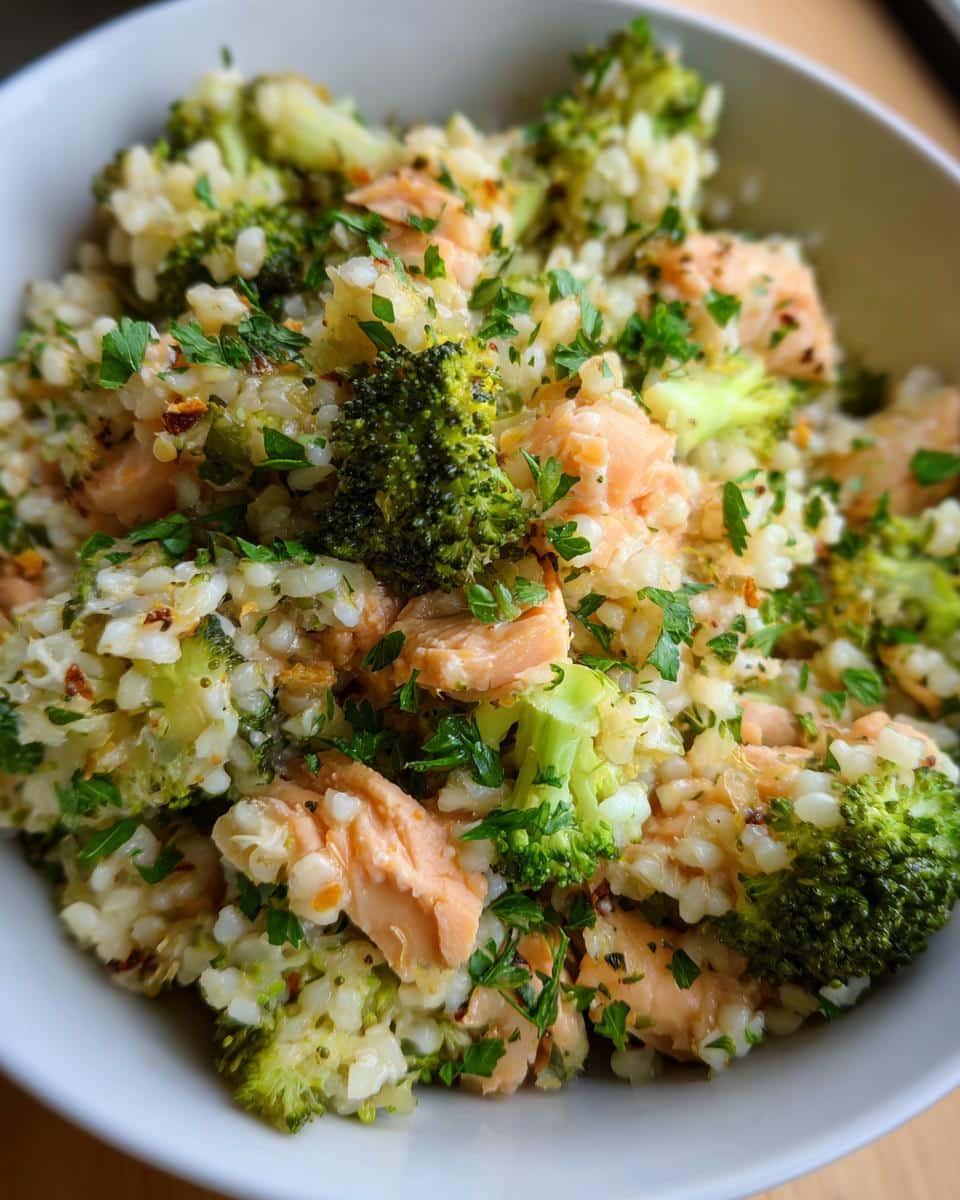 A bowl of Simple Salmon & Broccoli Dog Food, featuring chunks of salmon, broccoli florets, and rice, garnished with parsley.
