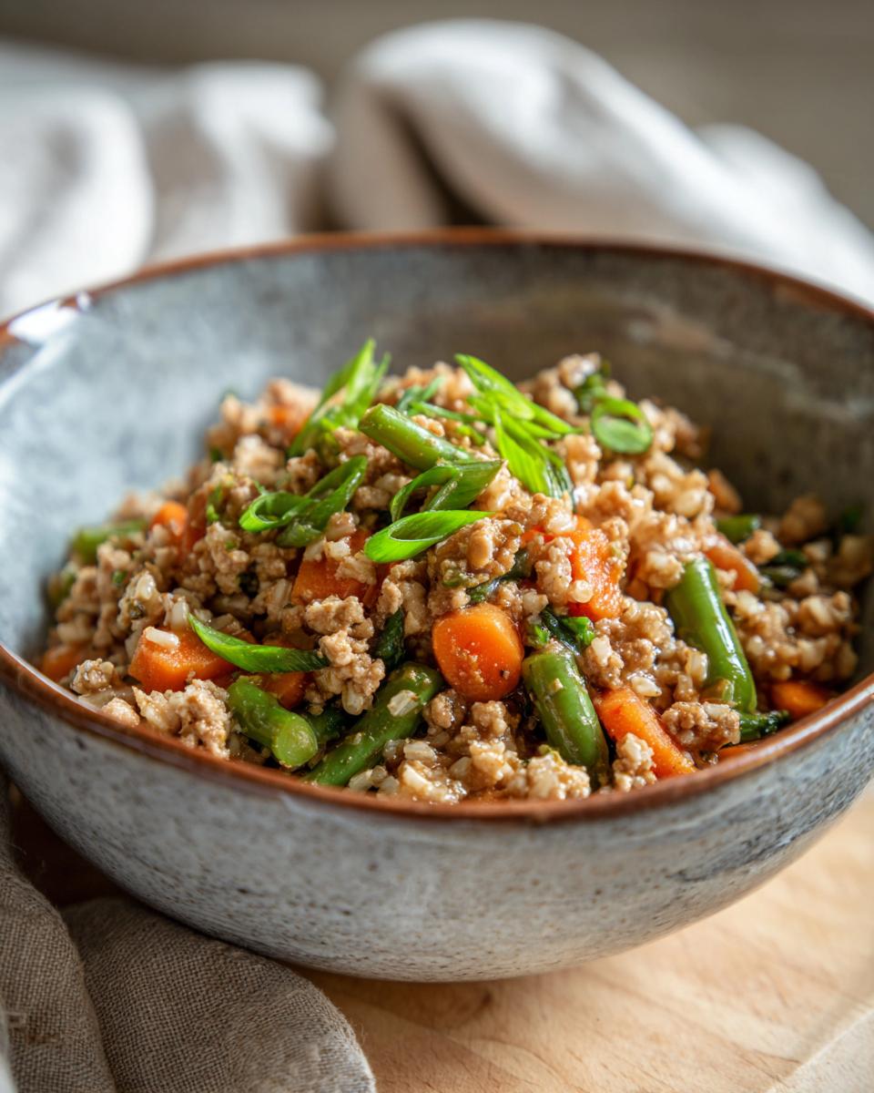 A delicious Small Dog Turkey & Veggie Bowl in a gray bowl, garnished with green onions. Healthy dog food recipe.