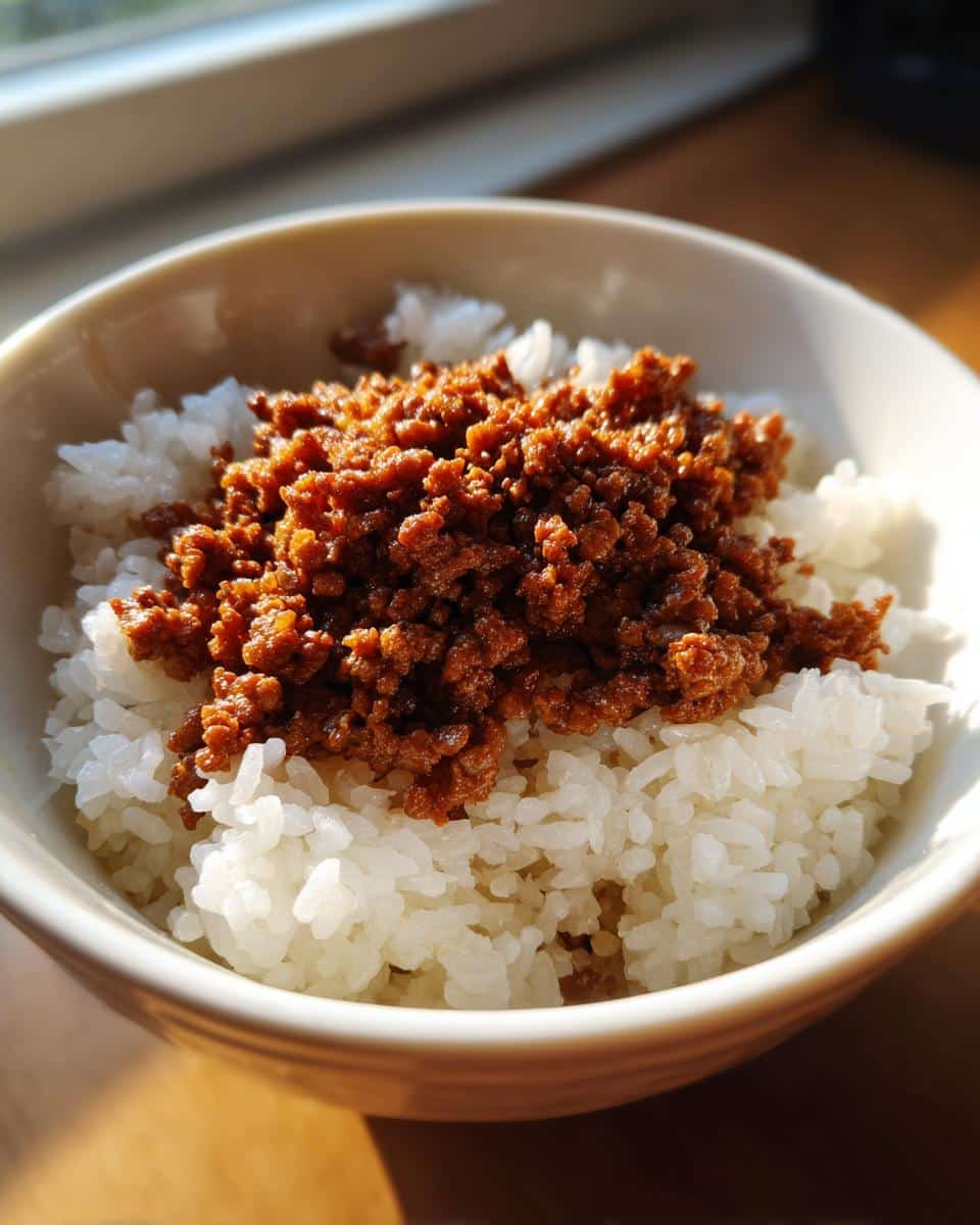 Close-up of a bowl containing white rice topped with seasoned ground beef for a Beef Rice Routine Dog Meal.