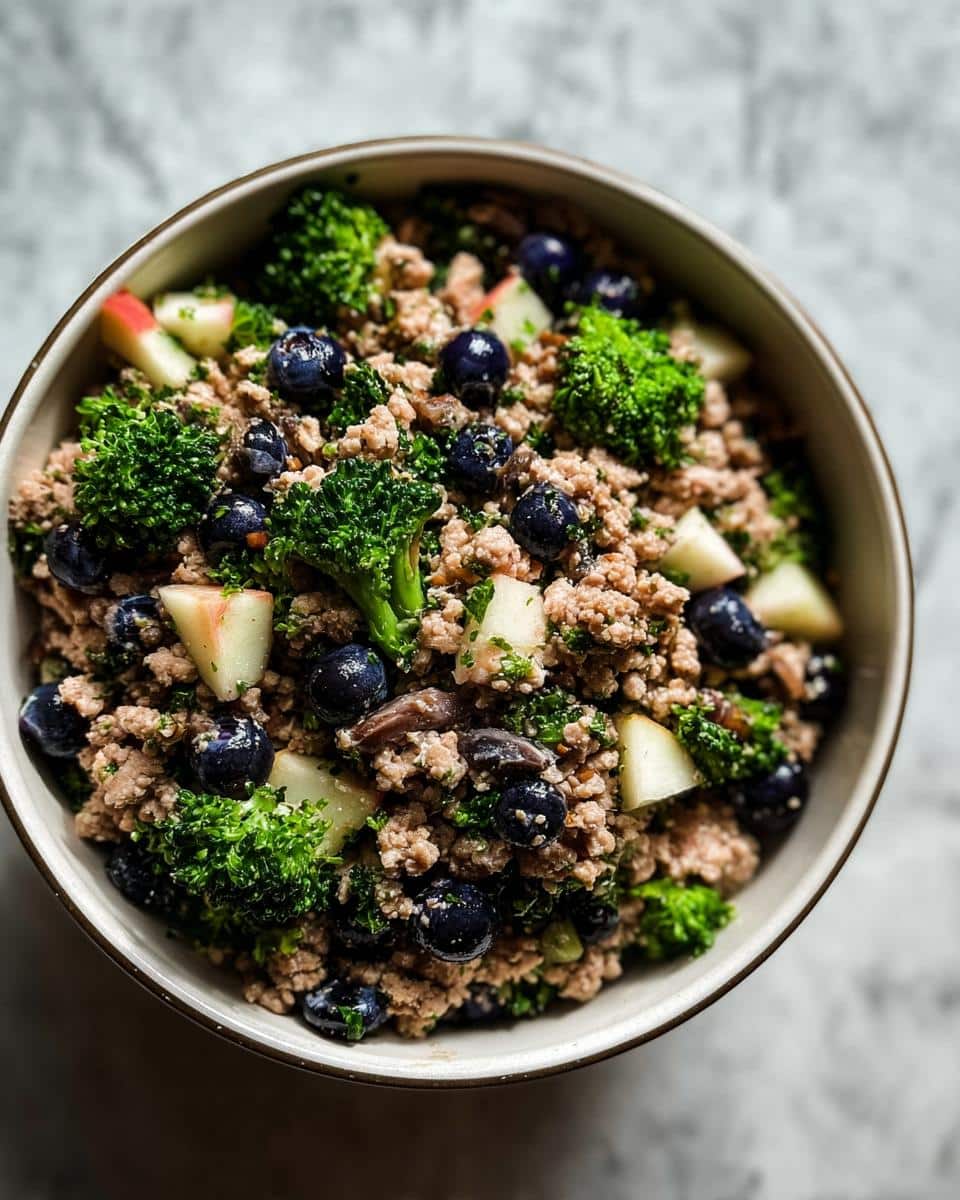 Close-up of a Holiday Leftover Turkey Bowl featuring ground turkey, blueberries, broccoli florets, and apple chunks.