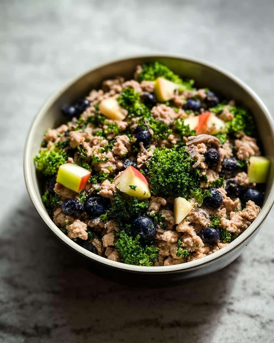 A close-up of a Holiday Leftover Turkey Bowl featuring ground turkey, bright green kale, blueberries, and diced red apples.