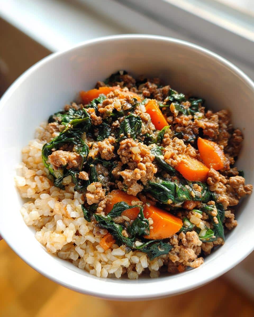 Close-up of a Turkey-Free Mixed Meat Dog Bowl featuring ground meat, spinach, carrots, and brown rice in a white bowl.