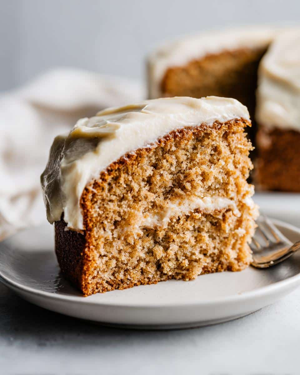 Close-up of a slice of Homemade Peanut Butter Dog Cake showing moist crumb and thick frosting.
