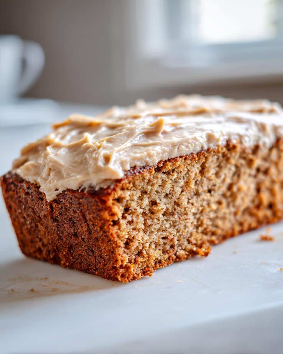 Close-up of a slice of rich, brown Peanut Butter & Banana Dog Cake topped with creamy peanut butter frosting.