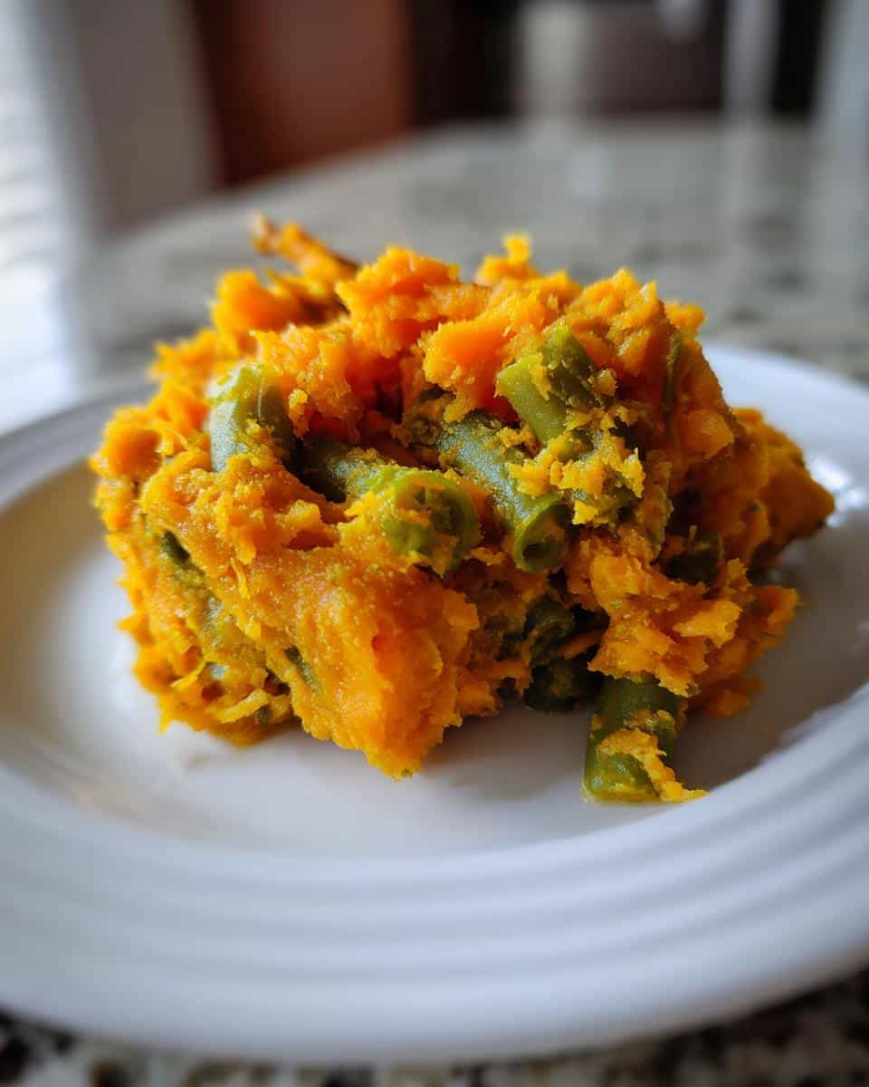 Close-up of a serving of Sweet Potato & Green Bean Mash for Dogs on a white plate.