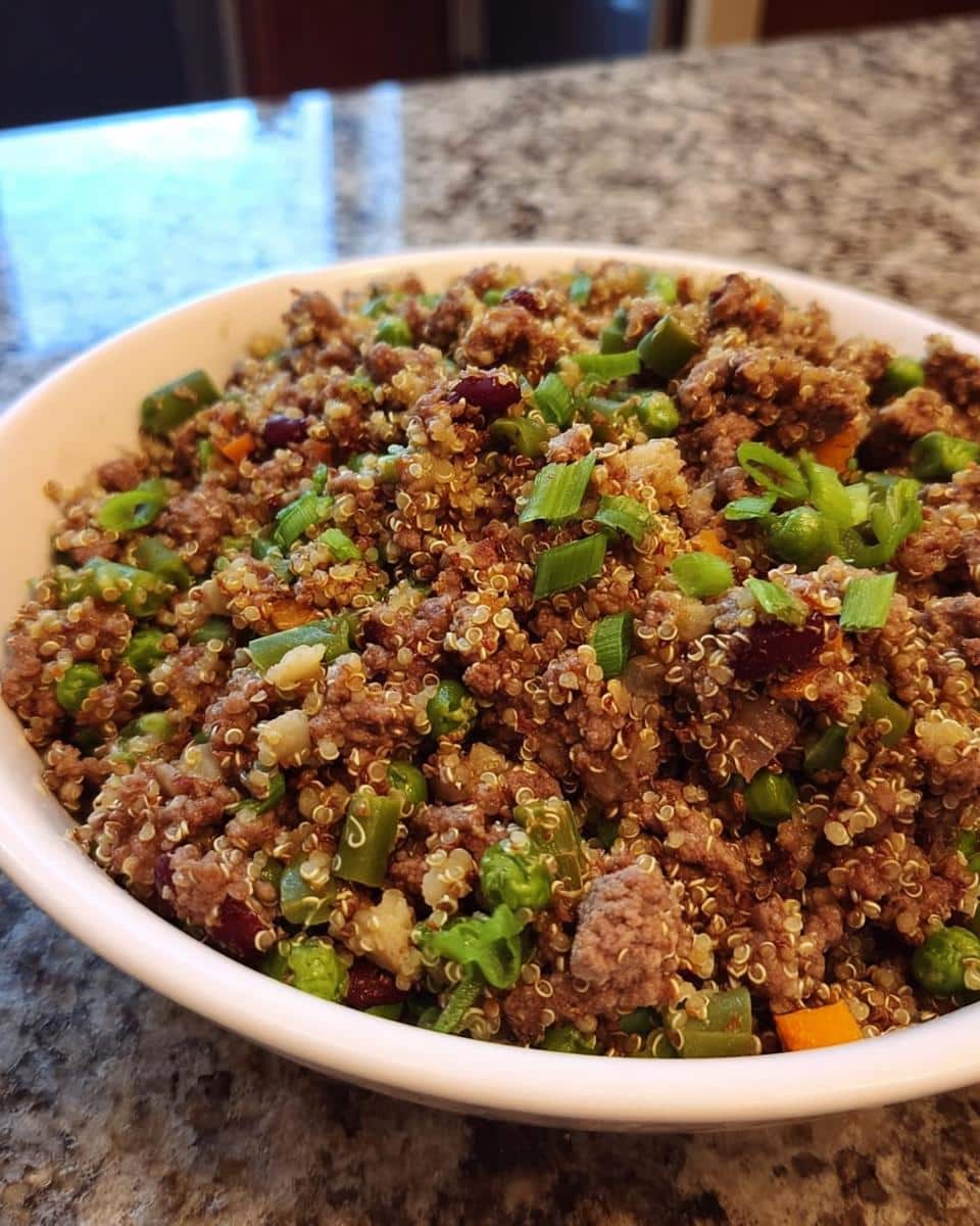 Close-up of homemade Beef, Quinoa & Green Beans Dog Food mix in a white bowl.