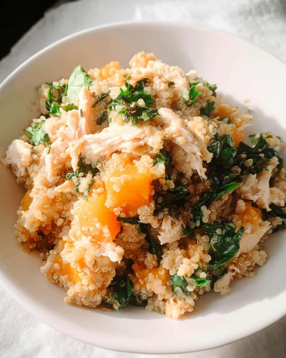 Close-up of Chicken, Quinoa & Spinach Mini-Batch Dog Food mix in a white bowl, showing shredded chicken, quinoa, and greens.