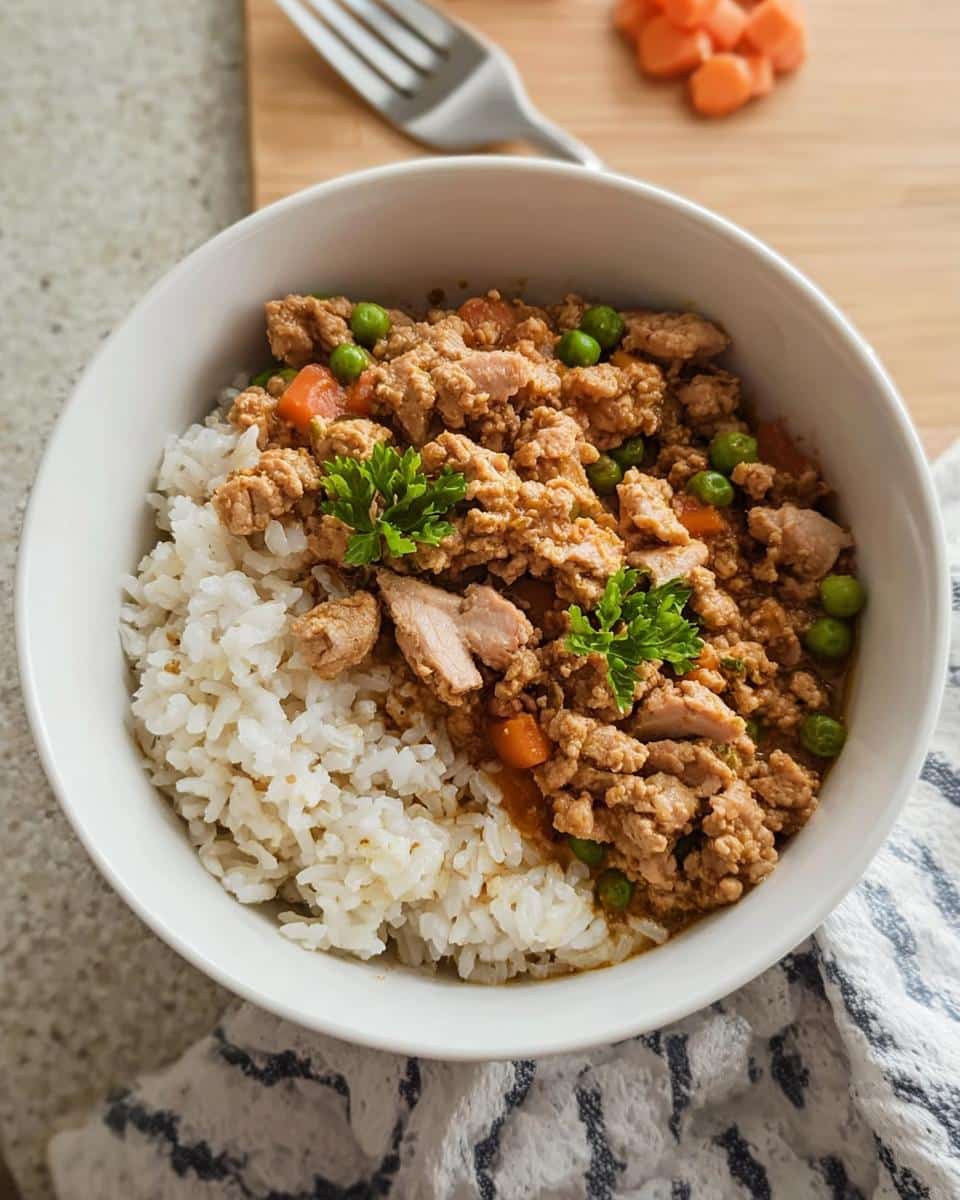 A bowl of homemade Chicken & Vegetable Stew for Puppies served over white rice, garnished with parsley.