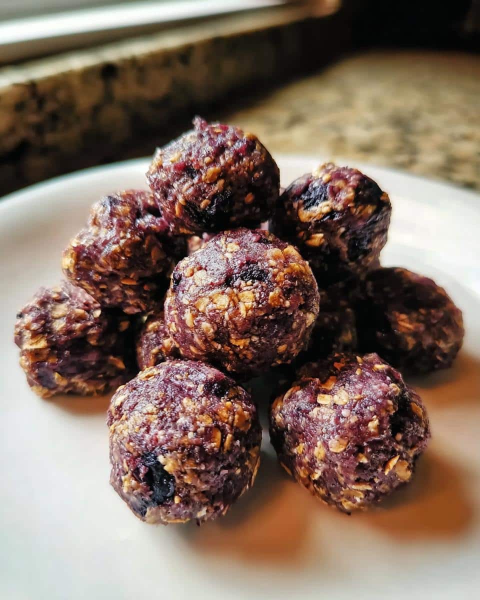 A pile of homemade dog treats made with venison, oatmeal & blueberries, shaped into small purple-hued balls.