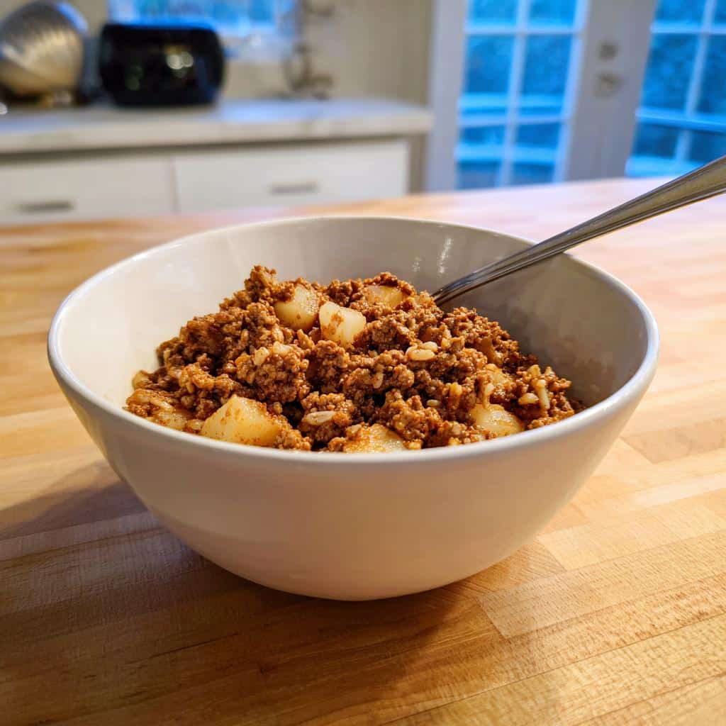 A white bowl filled with homemade Venison & Parsnip Dog Food, showing ground meat and chunks of parsnip.
