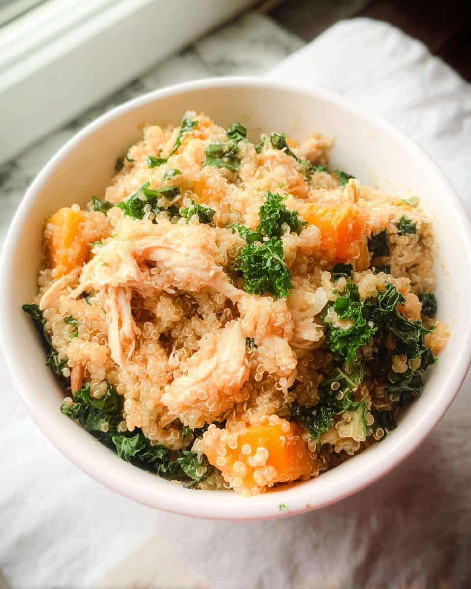 A white bowl filled with Vet-Approved Chicken, Quinoa & Spinach Dog Food, showing shredded chicken, quinoa, kale, and orange sweet potato chunks.